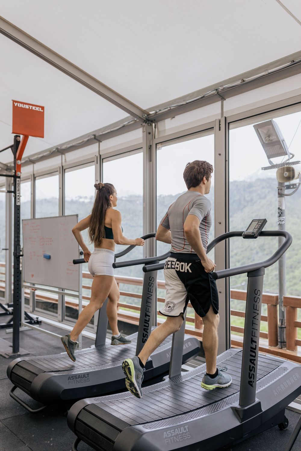 Man and woman running on curved non-motorised treadmills
