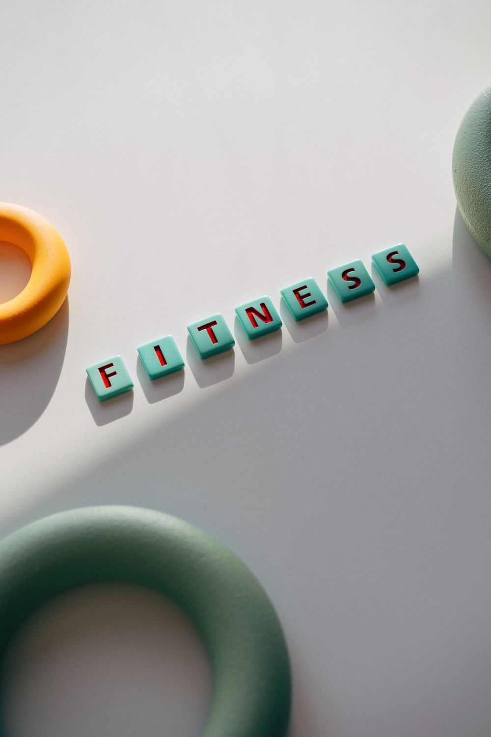 Green letter tiles spelling the word fitness on a white surface