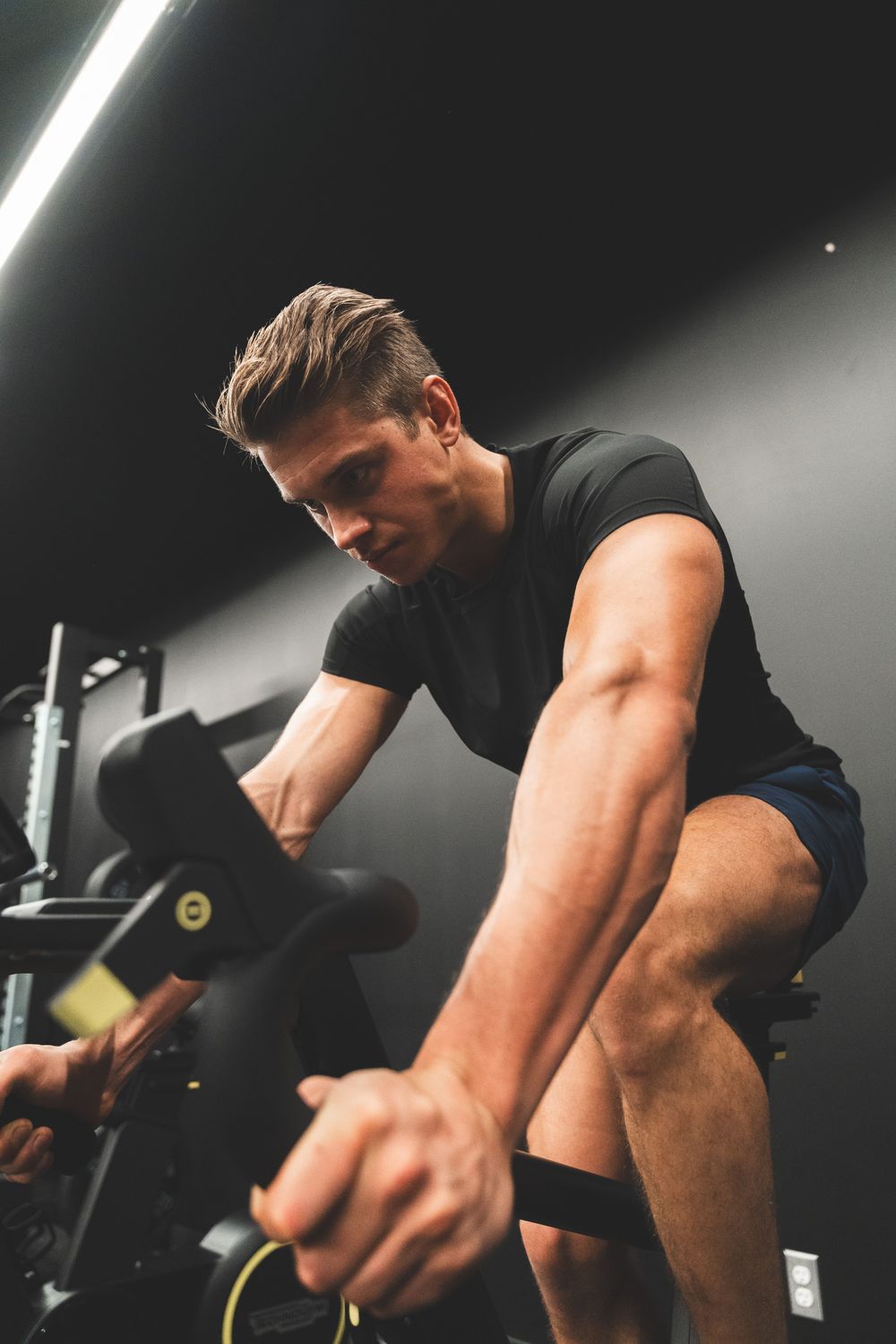 Man training on an indoor exercise bike under studio lighting