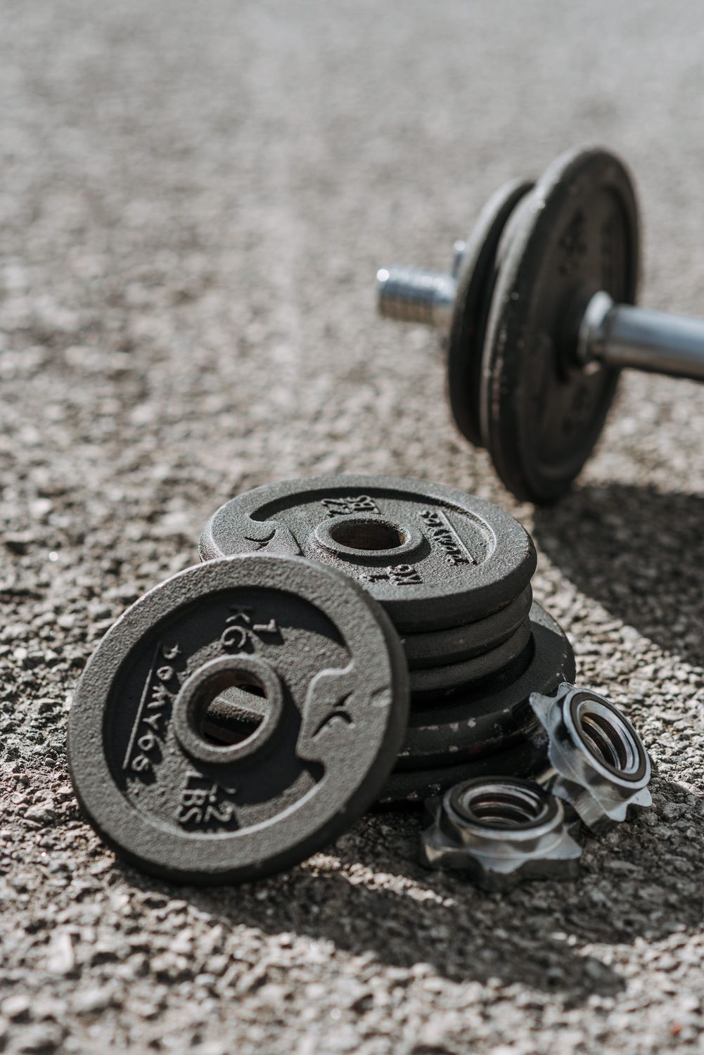 Cast-iron weight plates, spin-lock collars and a dumbbell handle on the ground